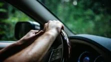 Driver's hands on the steering wheel of a car